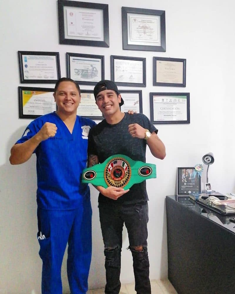 El boxeador Raúl Curiel con su cinturón de campeón junto a Mario Carpenter en el consultorio